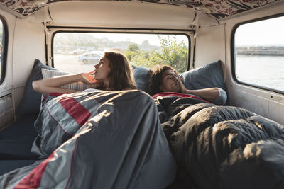 Male and female resting in camping van by seashore