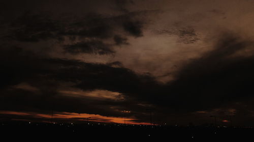 View of illuminated cityscape against cloudy sky