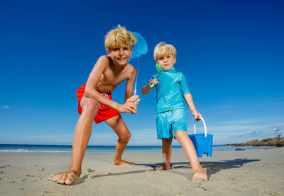 Full length of woman standing at beach against clear blue sky