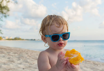Portrait of boy holding sunglasses on beach
