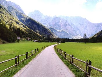 Scenic view of grassy field leading towards mountains against sky