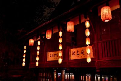 Low angle view of illuminated lanterns hanging by building