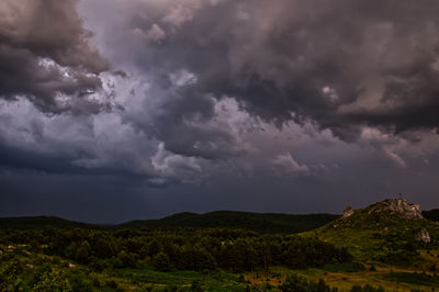 Scenic view of hills against stormy sky