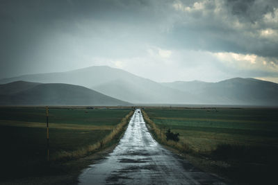 Road leading towards mountains against sky