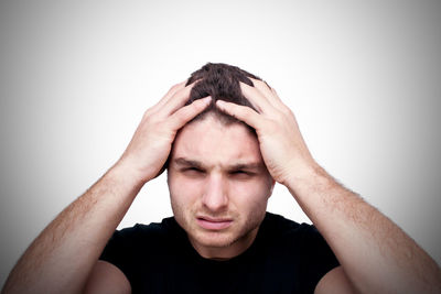 Portrait of man with headache against gray background