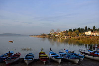 Sailboats moored in lake against sky