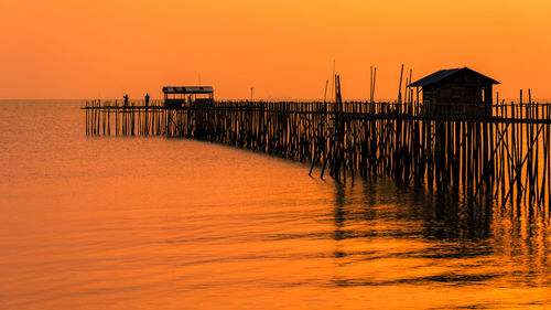 Pier over sea against sky during sunset