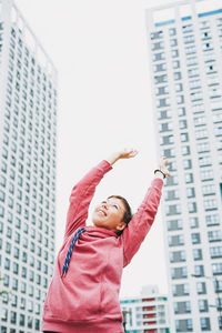 Low angle view of girl against building in city