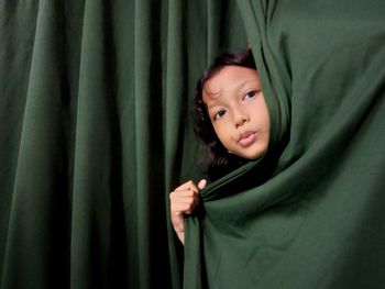 Portrait of girl hiding behind curtain