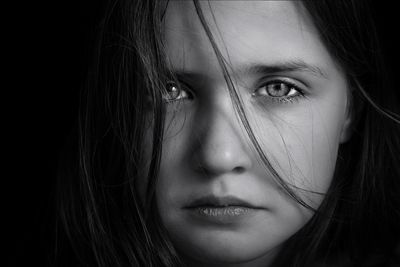 Close-up portrait of serious girl against black background