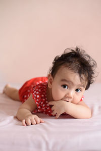 Portrait of cute baby girl lying on bed