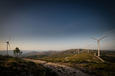 Wind turbines on field against sky