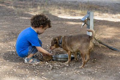 Boy drawing water from an animal fountain to give his little dog a drink