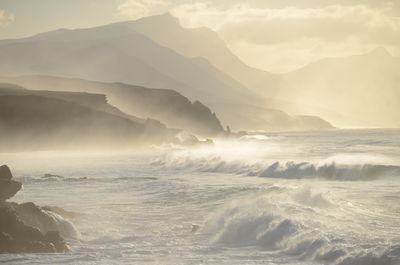 Scenic view of sea and mountains against sky during sunset