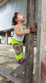 Girl standing against wooden wall