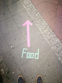 Low section of person standing by food text and arrow symbol on footpath