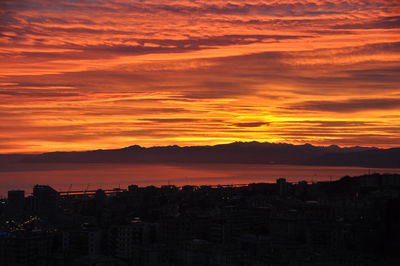 Silhouette buildings against orange sky