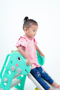Portrait of cute girl playing with toys against white background