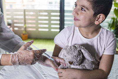 Doctor vaccinating a little boy's teddy bear