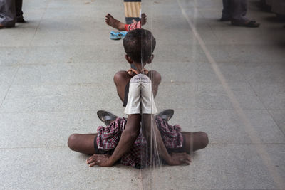 Boy sitting with reflection against the wall