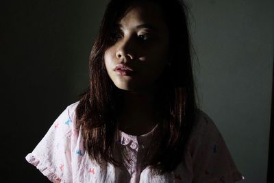 Close-up portrait of young woman against black background