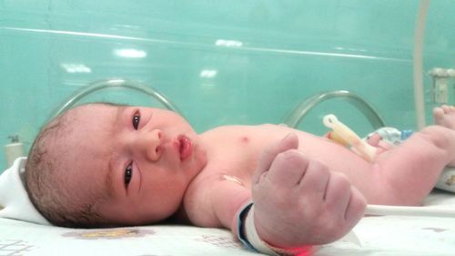 Close-up of newborn boy in incubator