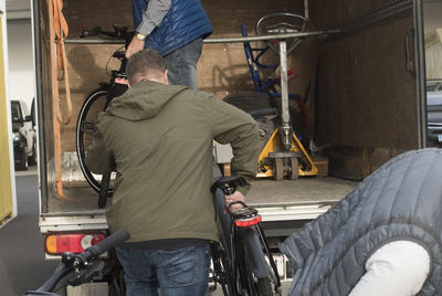 Rear view of man working with bicycle