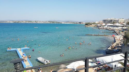 High angle view of sea by city against clear sky