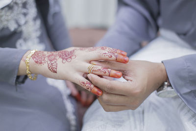 Midsection of groom exchanging ring with bride during wedding