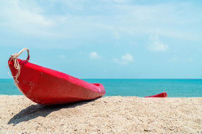 Red deck chairs on beach against sky