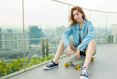 Full length of young woman sitting in city