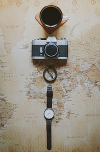 Directly above shot of coffee cup with camera and navigational compass on world map