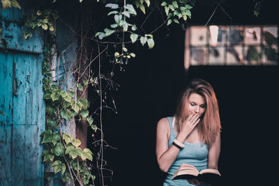 Woman reading book sitting outdoors