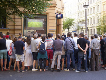 Rear view of people walking on street amidst buildings in city