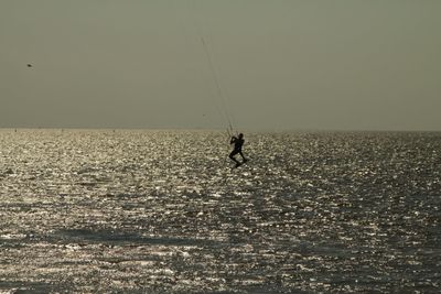Silhouette person on sea against sky