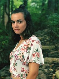 Portrait of beautiful young woman standing against trees