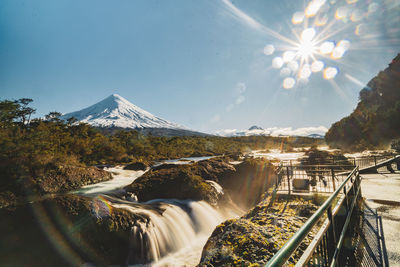 Scenic view of volcano and waterfalls against sky