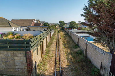 High angle view of old railroad track amidst walls against clear sky