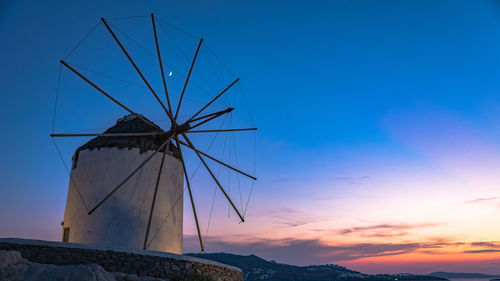 Low angle view of traditional windmill against sky at sunset