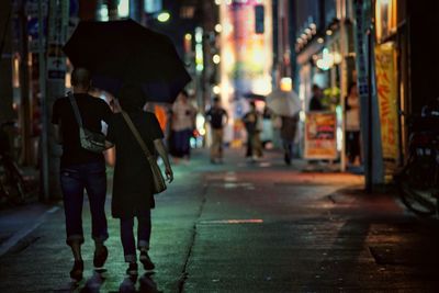 Full length of man walking in illuminated city at night