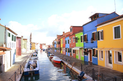 Boats in canal amidst buildings in city against sky