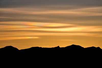 Silhouette mountains against dramatic sky during sunset