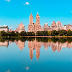 Reflection of buildings in lake against blue sky