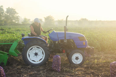 A farmer on a tractor works in the field. digging up the potato crop. farming and farmland