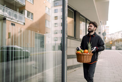 Young man delivering fruit basket in building