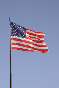 Low angle view of american flag against clear blue sky