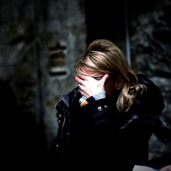 Portrait of young woman looking down while standing against wall