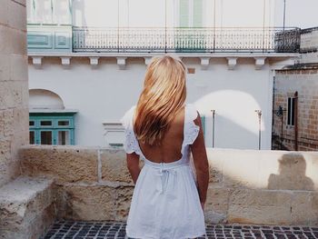 Rear view of woman standing against built structure