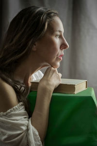 Woman in a white blouse with a carmen neckline with her hands resting on an old book 