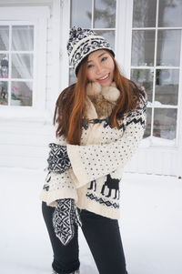 Young woman wearing warm clothes in winter against house